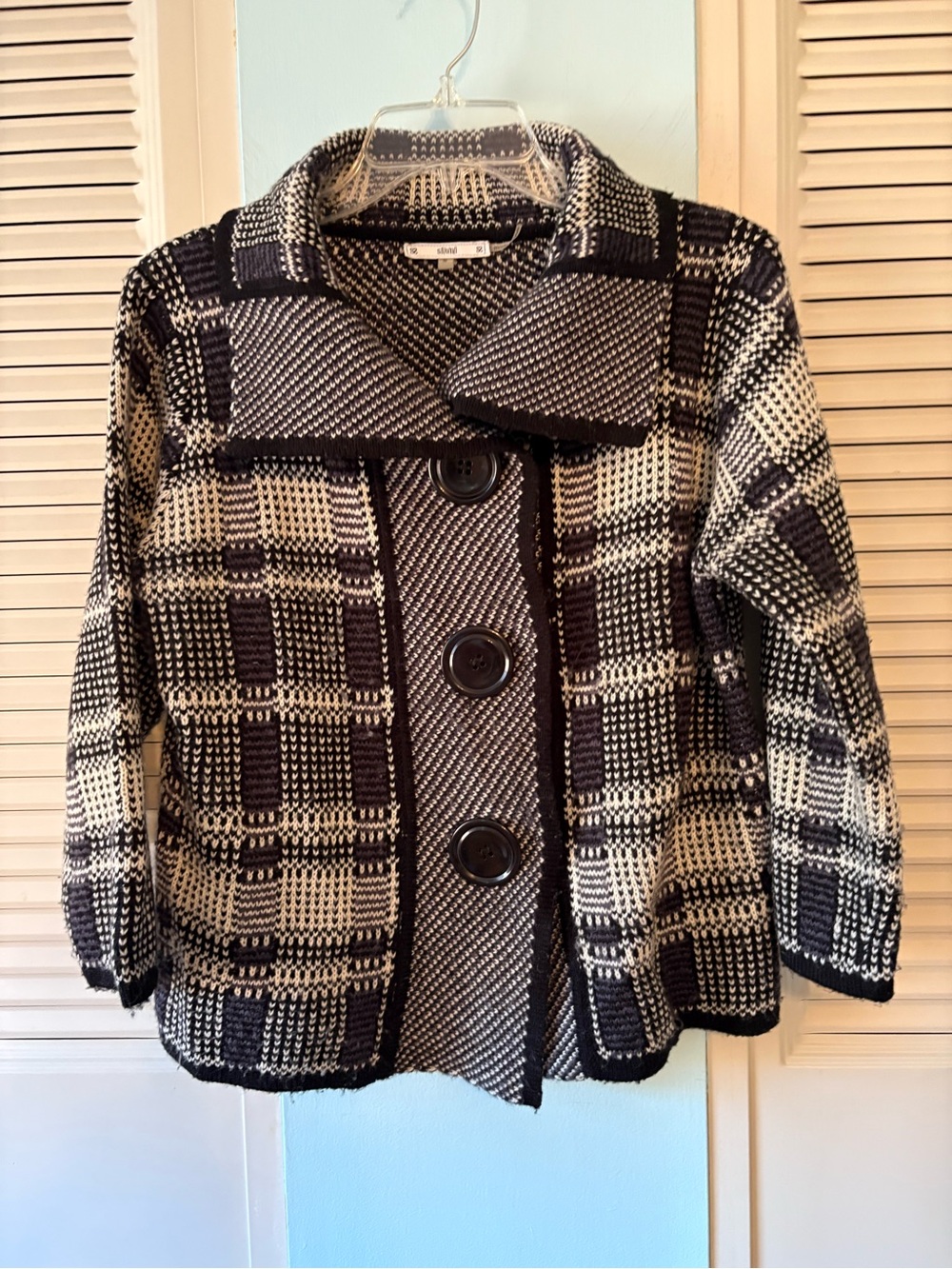 Black and white checked sweater with large buttons.